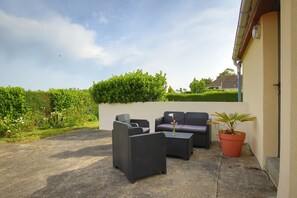 Een terras met rieten meubels, een plant in pot en een uitzicht op de lucht.