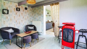 A modern living space with a sofa, dining table, and bar stools. - Holiday Home 'Gite De Pauline, Sainte-mère-église' with Private Terrace, Private Garden and Wi-Fi (Sainte-Mère-Église)