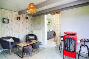 A modern living space with a sofa, dining table, and bar stools. - Holiday Home 'Gite De Pauline, Sainte-mère-église' with Private Terrace, Private Garden and Wi-Fi (Sainte-Mère-Église)
