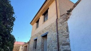 Une ruelle étroite avec un bâtiment en pierre, une petite fenêtre et une porte.