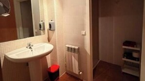 Une salle de bain équipée d’un lavabo, d’un miroir, d’un porte-serviettes et d’un radiateur.