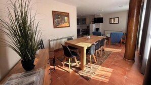 Un coin repas avec une table et des chaises en bois, une plante en pot et un tableau accroché au mur.
