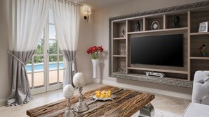 A living room with a large TV, wooden coffee table, and a pool view. - Villa Celeste - Casa del Sole (Tar-Vabriga)