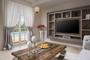 A living room with a large TV, wooden coffee table, and a pool view. - Villa Celeste - Casa del Sole (Tar-Vabriga)
