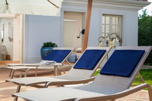 A row of sun loungers with blue cushions, a white building in the background, and a potted plant. - Villa Celeste - Casa del Sole (Tar-Vabriga)