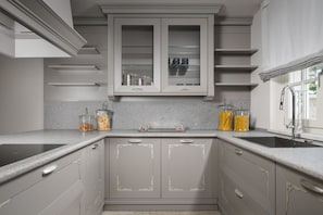 A kitchen with white cabinetry, a built-in stove, and a window with a towel. - Villa Celeste - Casa del Sole (Tar-Vabriga)