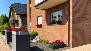 Une maison moderne en briques, dotée d’un balcon, de jardinières et d’un chemin en gravier.