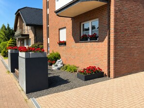 A modern brick house with a balcony, flower boxes, and a gravel pathway.