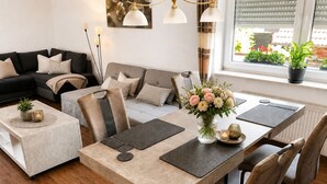 Un salon moderne avec un canapé, une table à manger, des chaises et une fenêtre agrémentée de plantes.