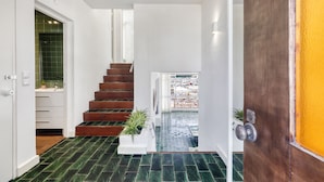 Un escalier menant à un balcon avec vue, une porte blanche et une plante en pot.