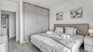 Une chambre avec un grand lit, une armoire et deux œuvres d’art accrochées au mur.