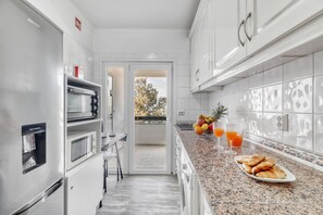 Eine moderne Küche mit Edelstahlgeräten, einer Granitarbeitsplatte und Blick durch eine offene Tür.