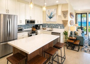 A modern kitchen with stainless steel appliances, a large island, and bar stools. - Napili Point | Oceanfront 1 BR Sleeps 4 | Car Incl. w/ 6+ Nights | NAP-B40 by KBM (Lahaina)