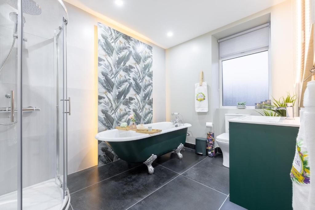Une salle de bain moderne avec une douche à parois de verre, une baignoire sur pieds, des toilettes et un lavabo.