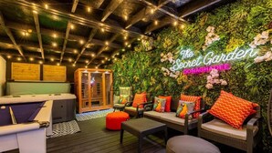 Un jardín interior acogedor con mesa de billar, asientos cómodos y un letrero de neón que dice 'The Secret Garden Donaghadee'.