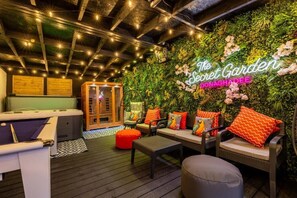 Een gezellige binnentuin met een pooltafel, comfortabele zithoek en een neonbord met de tekst 'The Secret Garden Donaghadee'.