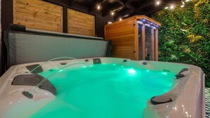 Un jacuzzi con gabinete de madera, pared con paneles de madera y pared verde con plantas.