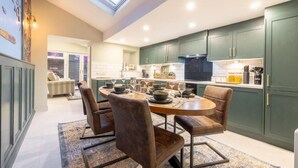 Una cocina moderna con tragaluz, armarios verdes y un comedor con mesa y sillas redondas.
