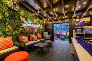Een knus binnentuin met een pooltafel, comfortabele zitplaatsen en een neonbord.