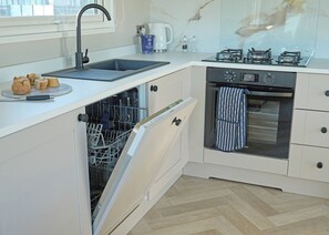 Eine Küche mit Geschirrspüler, Backofen und Kaffeemaschine auf der Arbeitsfläche.
