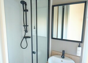 A modern bathroom with a glass-enclosed shower, a white sink, and a large mirror. - Premium 4 bedroom Holiday Home sleeps 8 (Landford, Nr Salisbury)