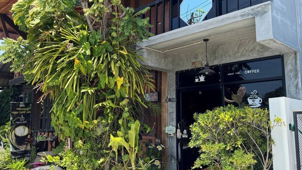 Ein Gebäude mit Holzbalkendecke, einem Eingang zu einem Café und mehreren Zimmerpflanzen.