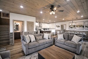 A spacious living area with a modern kitchen, a dining area with a long table, and a ceiling fan. - 4BR Luxury Cabin / Panoramic Mt Views / Game Rm, Bunk Rm, Playground, Firepit (Gatlinburg)