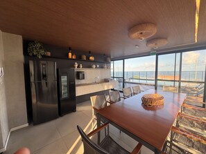 Eine moderne Küche mit einer großen Kochinsel, Edelstahlgeräten und Blick auf den Ozean.