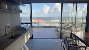 Eine moderne Küche mit Spüle, Grill und Meerblick durch große Fenster.