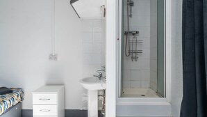 A modern bathroom with a shower, sink, and a small bedside table. - Room 1 - The Archers (Southampton)