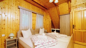 A wooden-paneled room with a bed, bedside tables, and a door. - Paradise in the countryside - pool, whirlpool & absolute tranquillity (Breze)