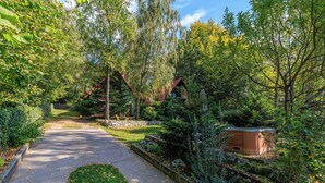 A garden path leading to a wooden cabin, surrounded by lush greenery and a stone wall. - Paradise in the countryside - pool, whirlpool & absolute tranquillity (Breze)