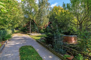 A garden path leading to a wooden cabin, surrounded by lush greenery and a stone wall. - Paradise in the countryside - pool, whirlpool & absolute tranquillity (Breze)