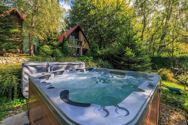 A hot tub in a lush garden with a wooden cabin in the background. - Paradise in the countryside - pool, whirlpool & absolute tranquillity (Breze)