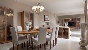 A dining area with a wooden table, six chairs, a chandelier, and a television in the background. - Villa Bianca - Casa del Sole (Tar-Vabriga)