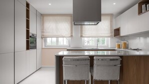 A modern kitchen with a central island, bar stools, built-in appliances, and large windows. - Villa Bianca - Casa del Sole (Tar-Vabriga)