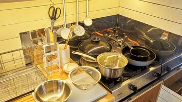 A kitchen with a stove, pots, pans, and various utensils.