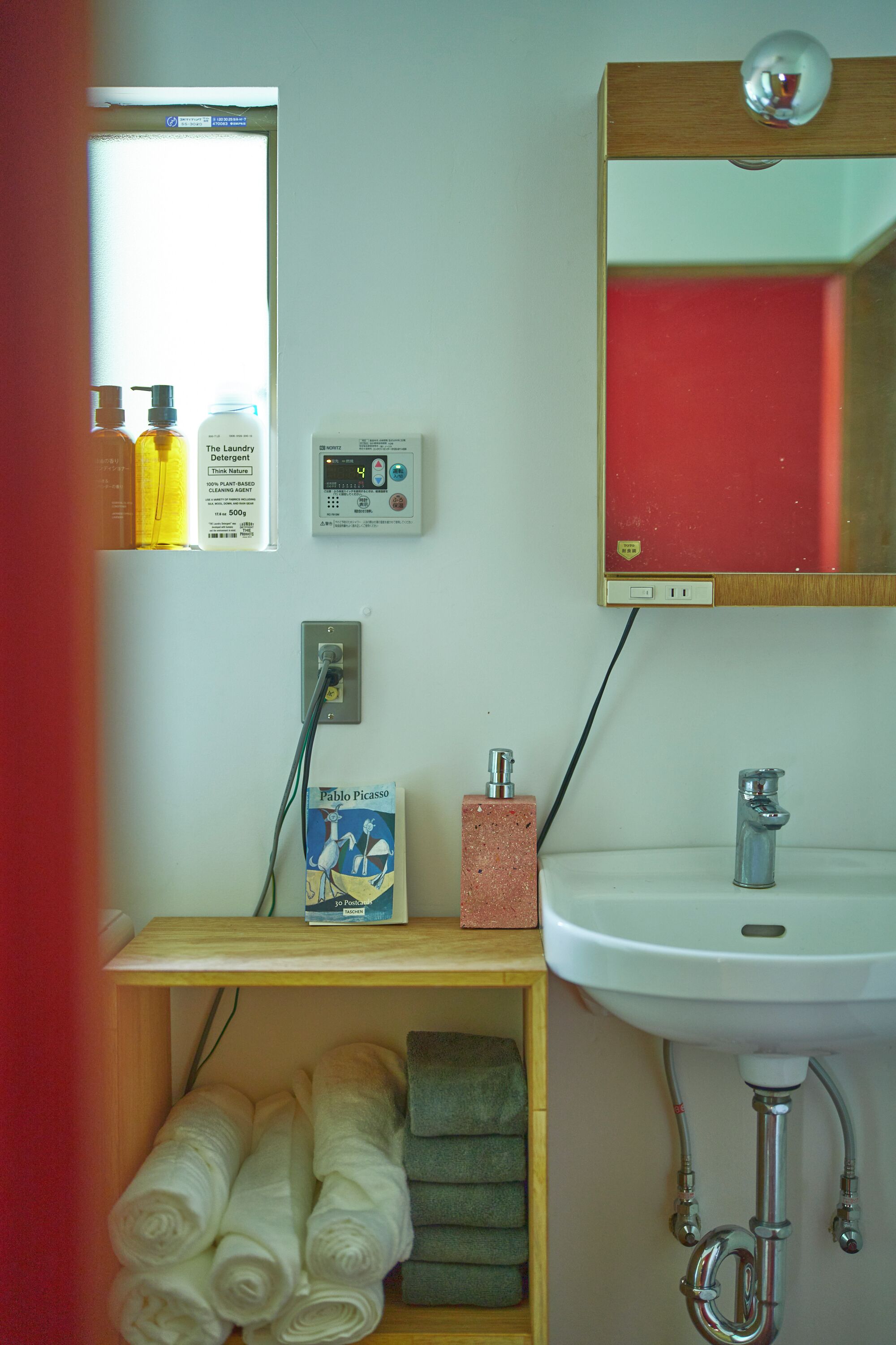 Ein Badezimmer mit einem weißen Waschbecken, einem Spiegel, einer Ablage für Toilettenartikel und Handtüchern.