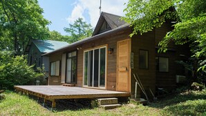 Una cabaña de madera con terraza, ventanas grandes y una puerta.