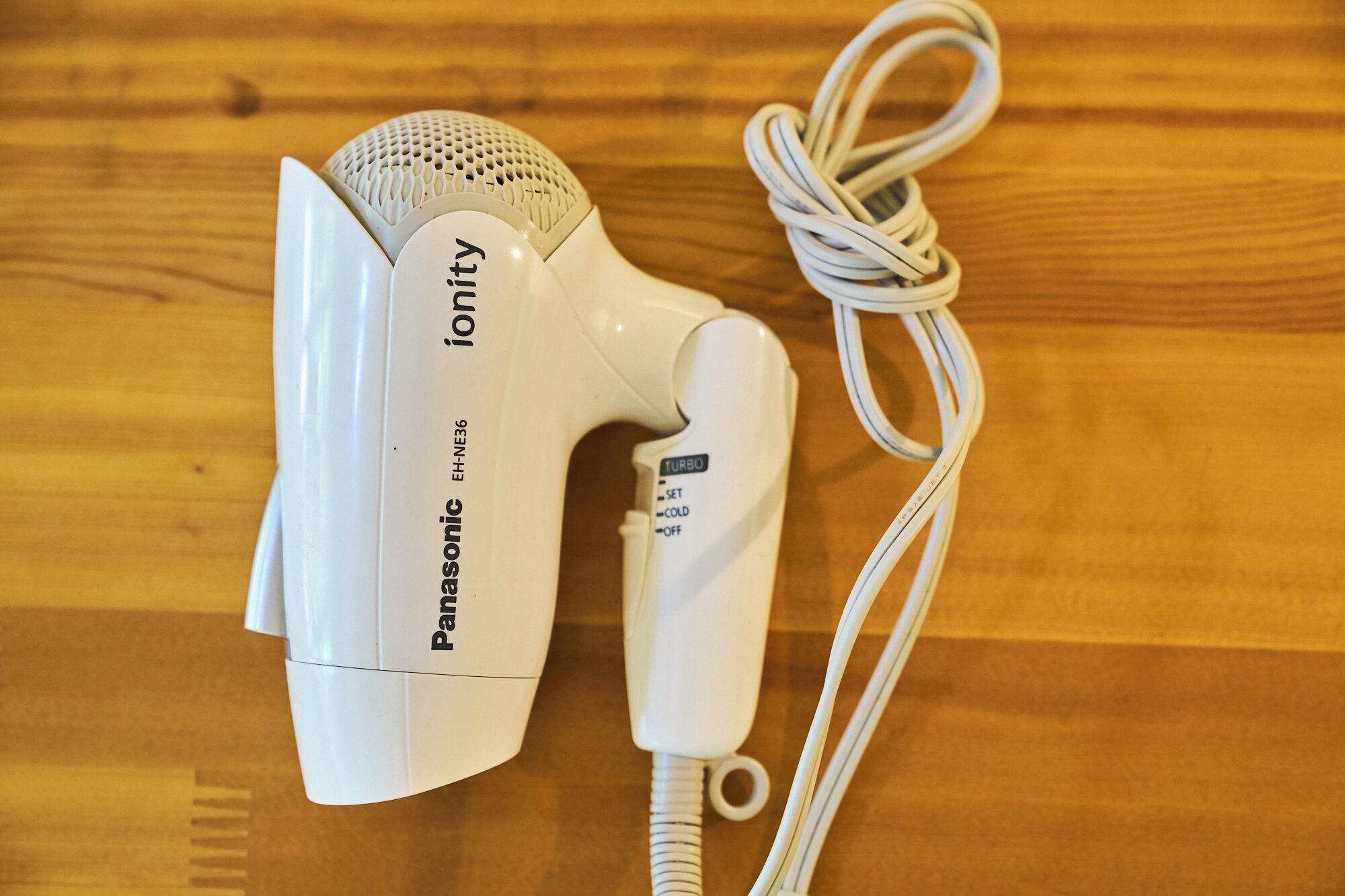 Un secador de pelo Panasonic Ionity con cable sobre una superficie de madera.