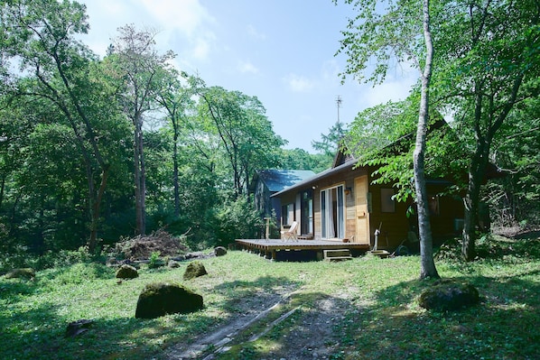 A cabin in a forest with a deck and a covered porch. - Kaneko sanso KK1 (Hokuto city Oizumi cho Nishiide)
