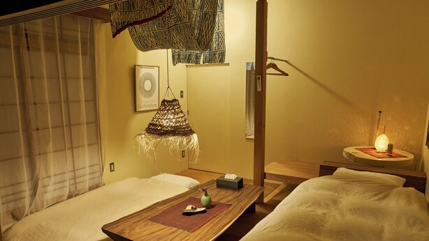 Una habitación tradicional japonesa con suelo de tatami, una mesa de madera baja y una decoración textil colgante.
