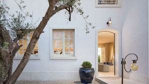 Un bâtiment blanc avec une fenêtre, une plante en pot et une lampe.