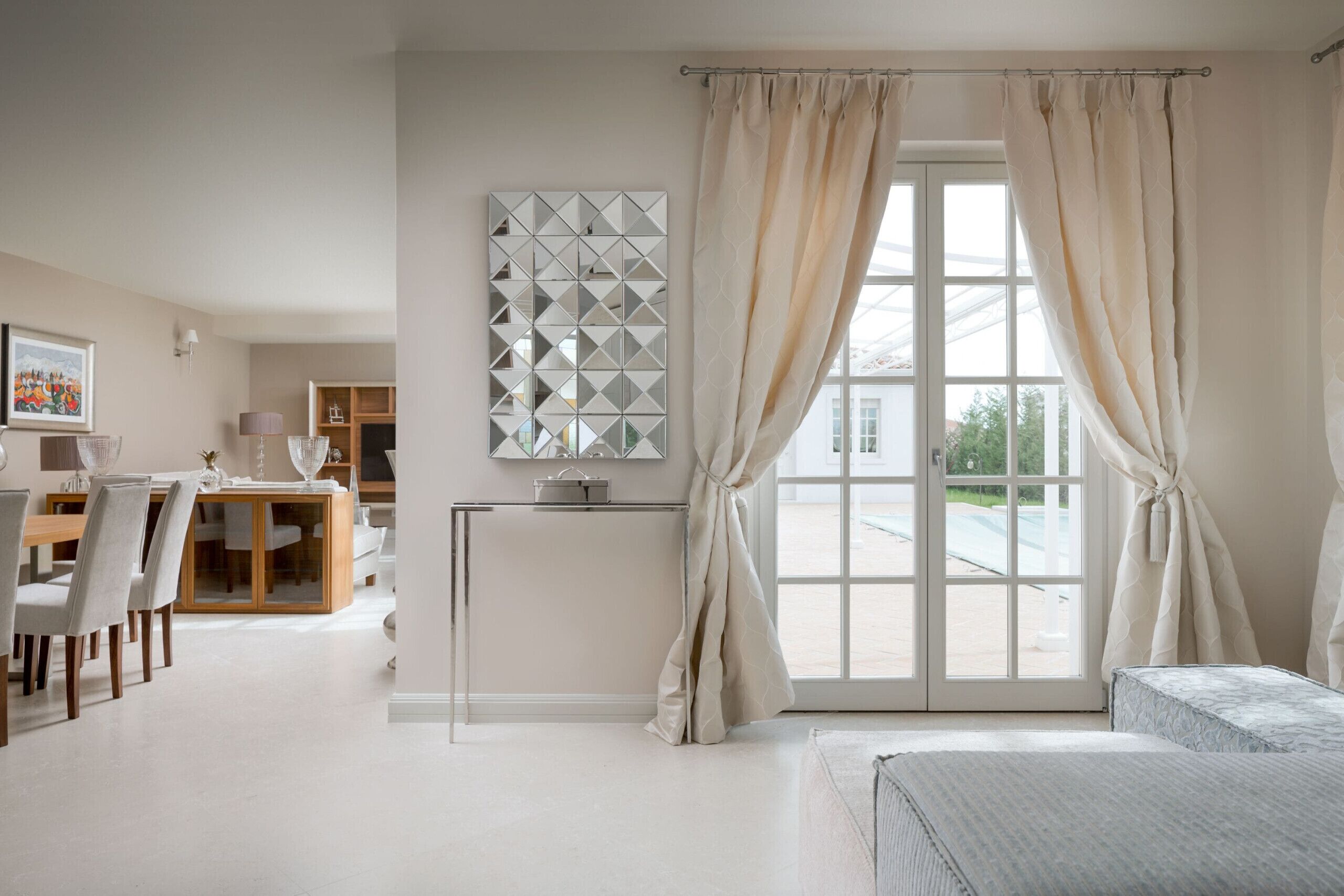 A modern bedroom with a large window, a bed, a bedside table, and a desk with chairs.