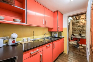 Une cuisine de taille réduite avec des placards rouges, un évier et un four à micro-ondes.