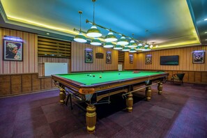 A pool table with a green felt surface, surrounded by wooden paneling and framed pictures on the walls. - Beijing hotel Ulaanbaatar (Ulaanbaatar)