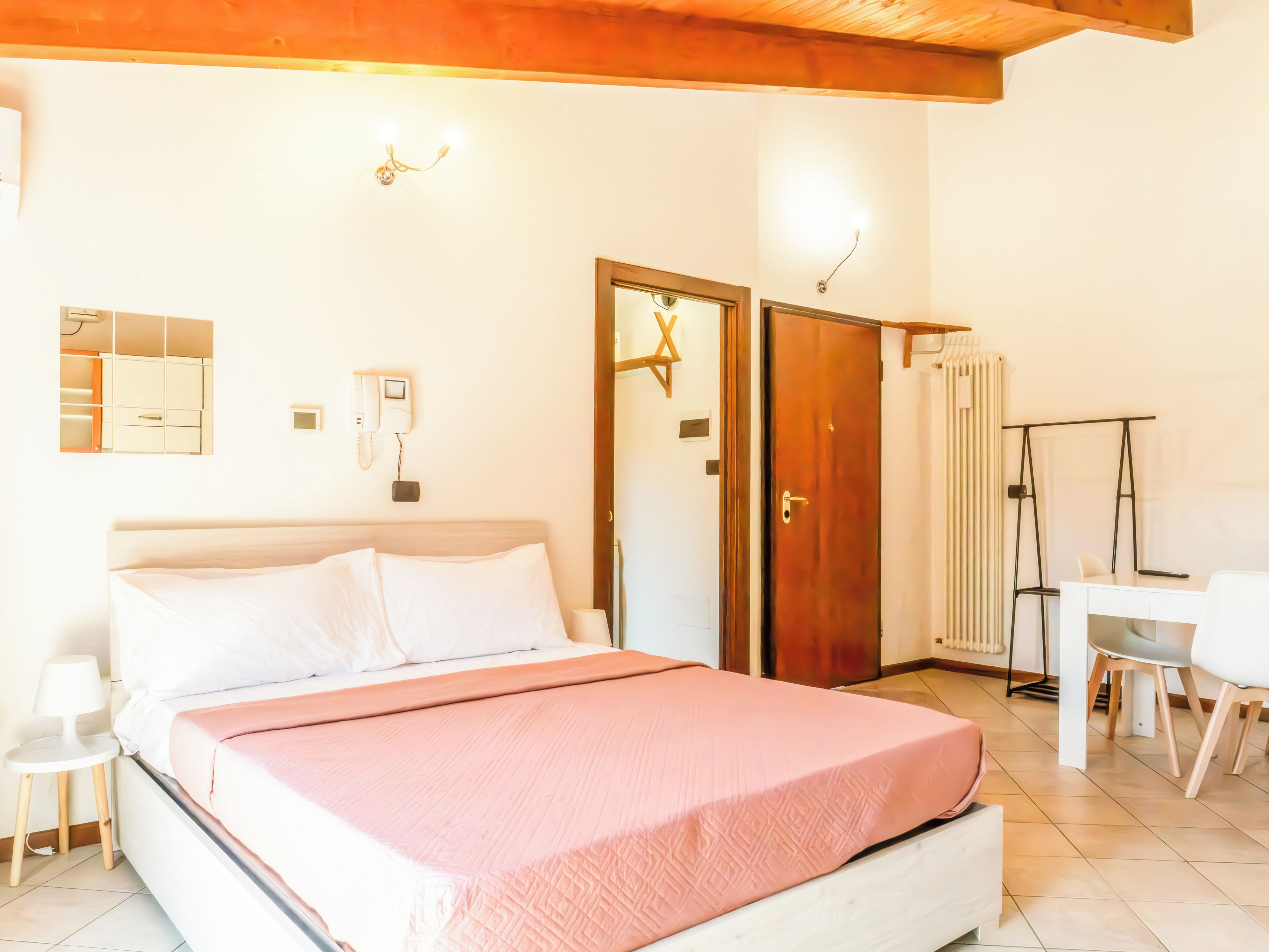 Un dormitorio con cama, mesita de noche, lámpara, armario y un escritorio con sillas.