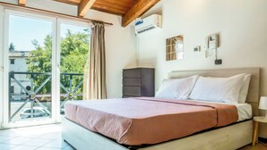 A bedroom with a bed, a dresser, a thermostat, and a view of the outside. - Living 68 (Forlì)