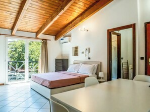 A bedroom with a bed, bedside table, lamp, and a view of the outdoors. - Living 68 (Forlì)