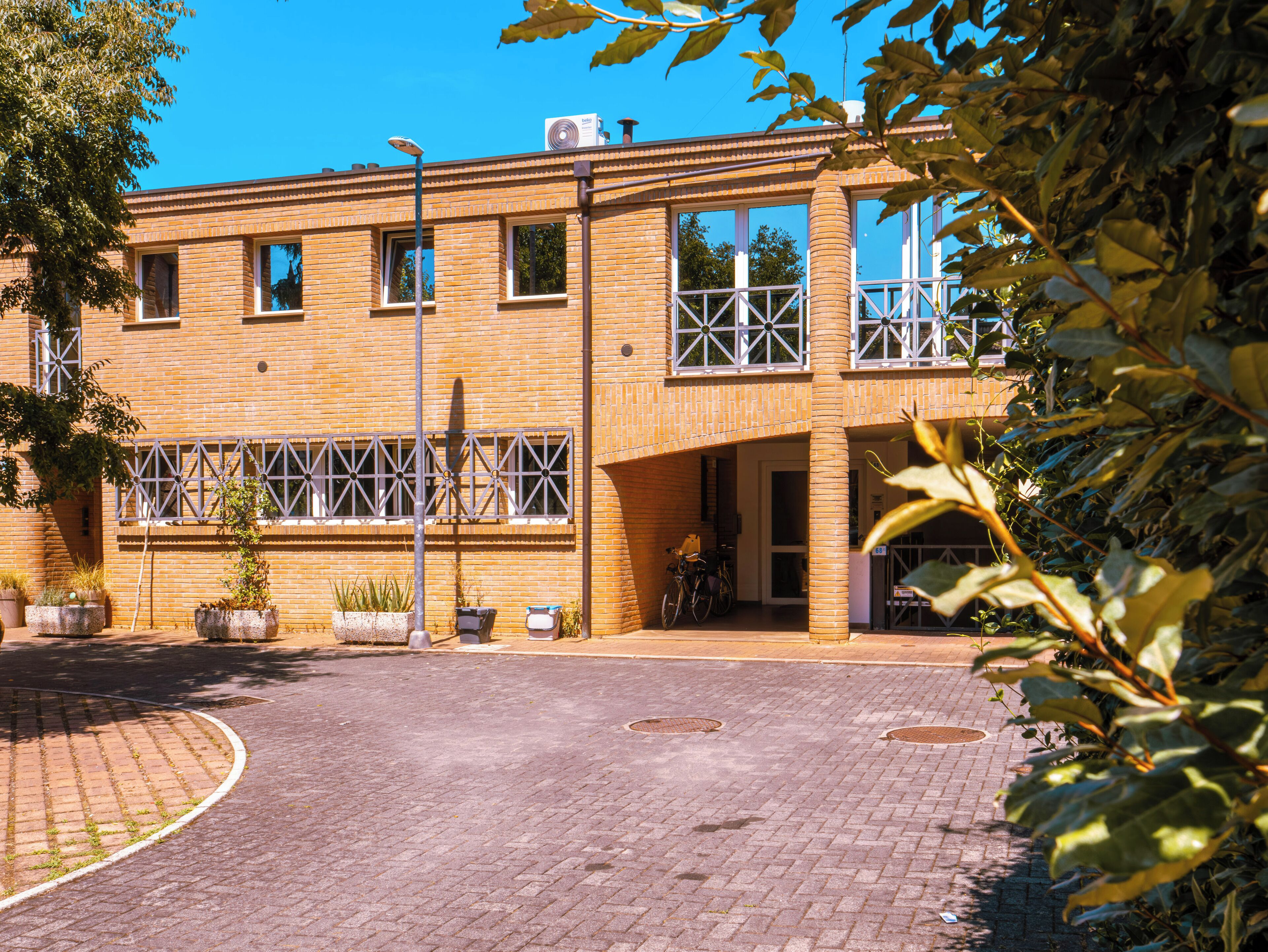 A building with a brick facade, large windows, and a paved courtyard.